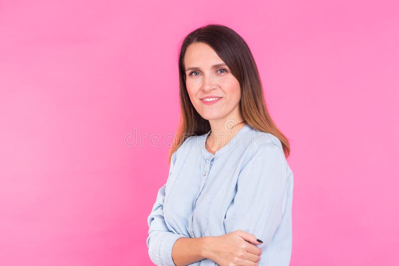 Mujer sonriente en la camisa que presenta en estudio en fondo rosado fotografía de archivo libre de regalías Mujer sonriente en la camisa que presenta en estudio en fondo rosado fotografía de archivo libre de regalías