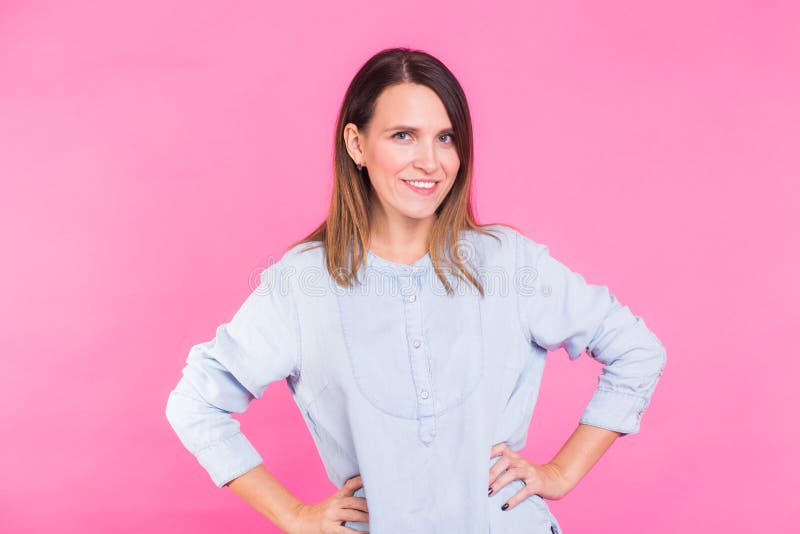 Mujer sonriente en la camisa que presenta en estudio en fondo rosado imagenes de archivo Mujer sonriente en la camisa que presenta en estudio en fondo rosado imagenes de archivo