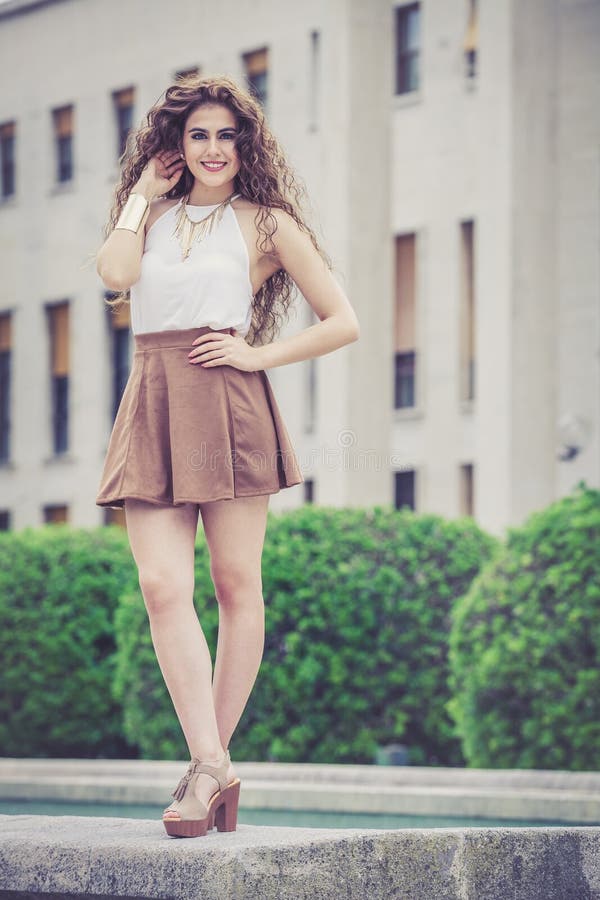 Mujer sonriente hermosa con el pelo rizado Mirada elegante urbana fotografía de archivo Mujer sonriente hermosa con el pelo rizado Mirada elegante urbana fotografía de archivo