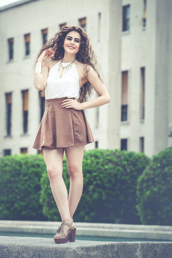 Mujer sonriente hermosa con el pelo rizado Mirada elegante urbana foto de archivo Mujer sonriente hermosa con el pelo rizado Mirada elegante urbana foto de archivo