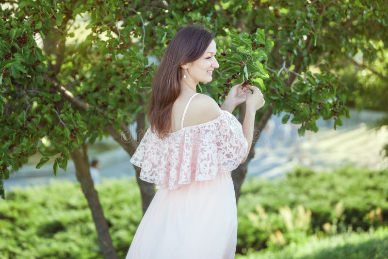 Mujer sonriente hermosa en un vestido en el jardín imagen de archivo Mujer sonriente hermosa en un vestido en el jardín imagen de archivo