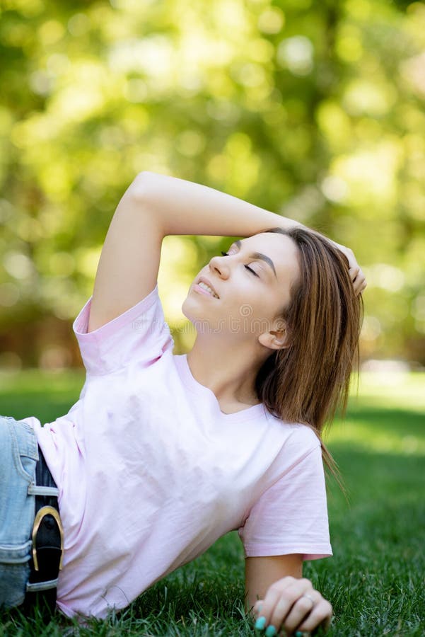 Mujer sonriente hermosa que miente en una hierba al aire libre fotos de archivo Mujer sonriente hermosa que miente en una hierba al aire libre fotos de archivo