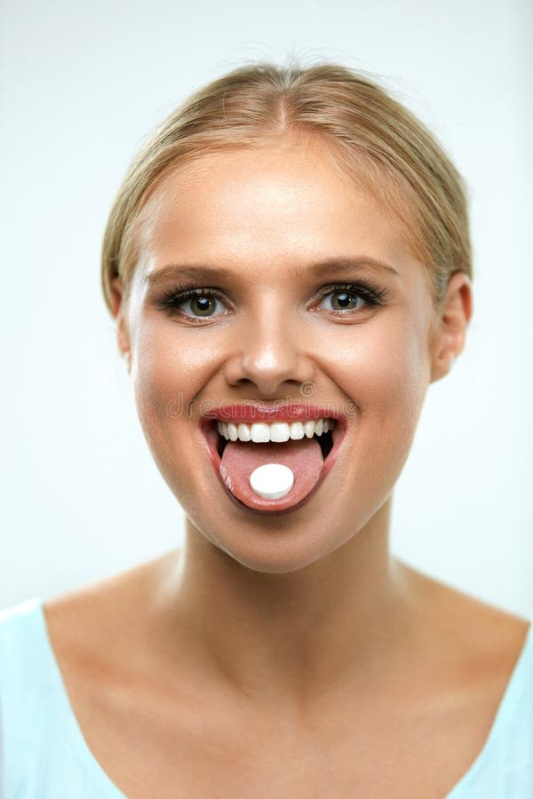 Mujer sonriente hermosa que toma la medicina, sosteniendo la píldora en la lengua fotos de archivo libres de regalías Mujer sonriente hermosa que toma la medicina, sosteniendo la píldora en la lengua fotos de archivo libres de regalías
