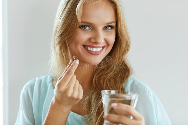 Mujer sonriente hermosa que toma la píldora de la vitamina Suplemento dietético
