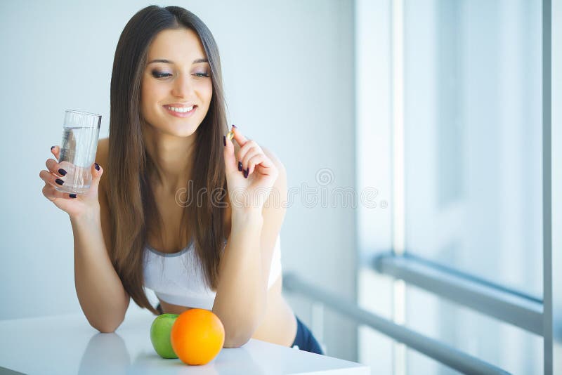 Mujer sonriente hermosa que toma la píldora de la vitamina Suplemento dietético