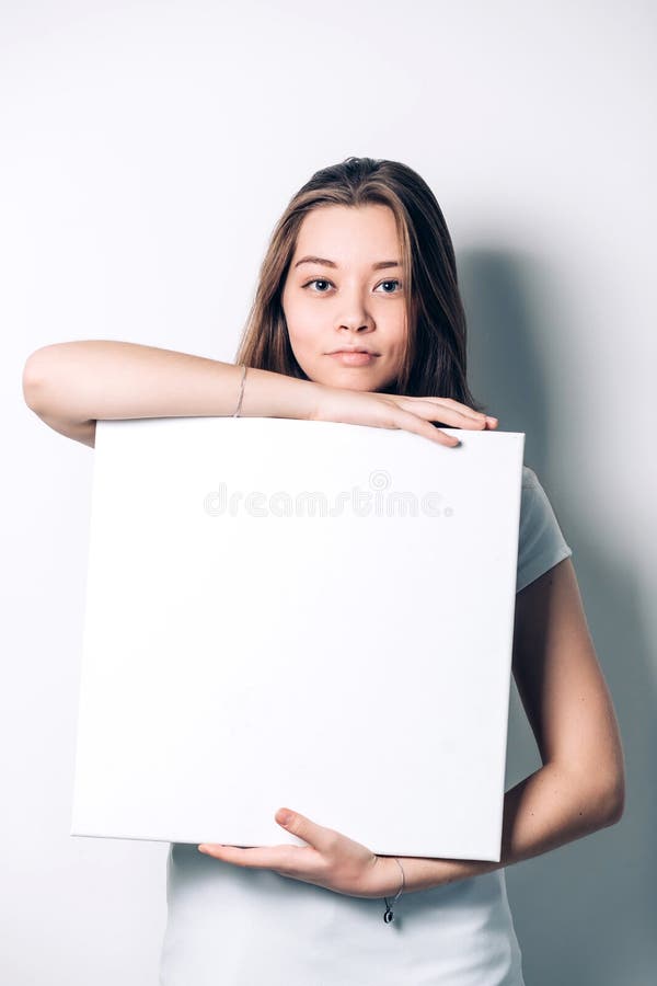 Mujer sonriente joven que sostiene una hoja de papel en blanco fotografía de archivo libre de regalías Mujer sonriente joven que sostiene una hoja de papel en blanco fotografía de archivo libre de regalías