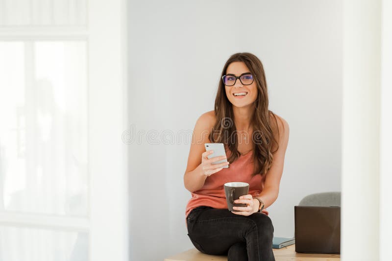 Mujer sonriente que habla en el teléfono que toma un descanso para tomar café imagen de archivo libre de regalías Mujer sonriente que habla en el teléfono que toma un descanso para tomar café imagen de archivo libre de regalías