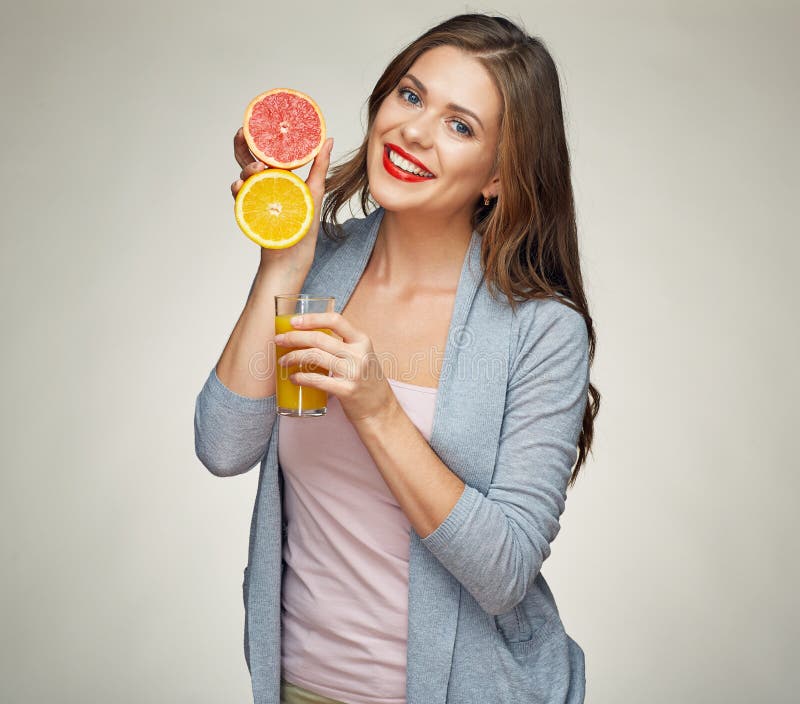 Mujer sonriente que sostiene el jugo de cristal con a medias anaranjado y grapefrui imagenes de archivo Mujer sonriente que sostiene el jugo de cristal con a medias anaranjado y grapefrui imagenes de archivo
