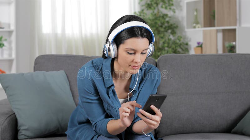 Mujer sorprendente que escucha la música en un sofá