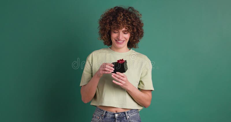 Mujer sorprendida abriendo caja de regalo en estudio de color verde metrajes