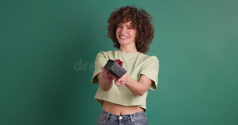 Mujer sorprendida abriendo caja de regalo en estudio de color verde