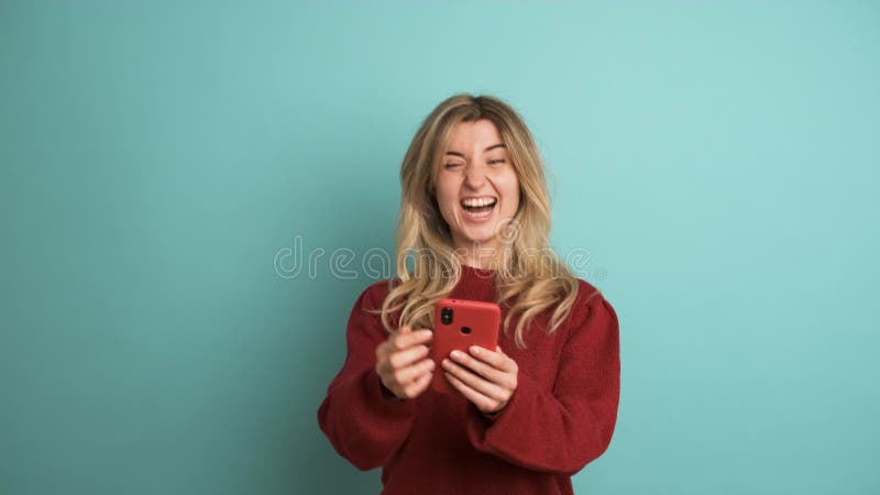 Mujer sorprendida con celulares celebrando la victoria en estudio azul almacen de video