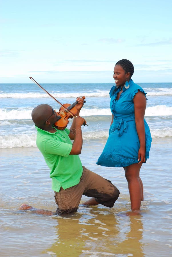 Mujer sorprendida por el músico de la playa fotos de archivo libres de regalías Mujer sorprendida por el músico de la playa fotos de archivo libres de regalías