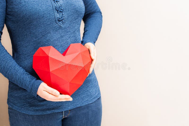 Mujer sosteniendo el corazón rojo con forma de diamante poligonal delante de su cuerpo