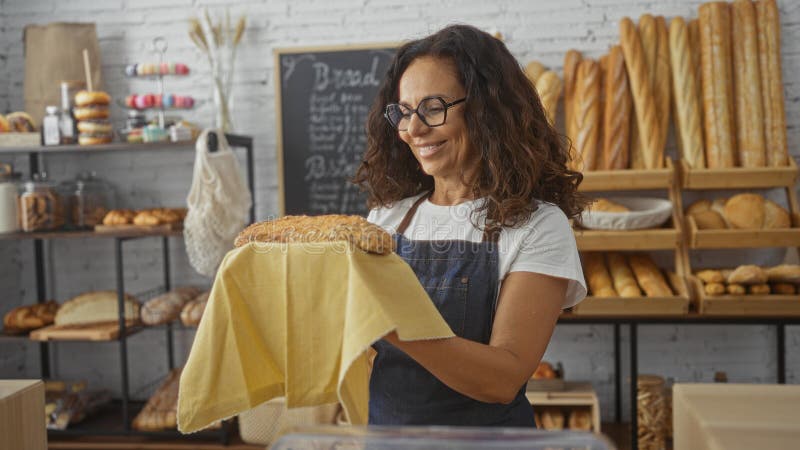 Mujer sosteniendo el pan recién horneado en una sala de panadería con estanterías de pan variado y bollería de fondo con fotos de archivo libres de regalías