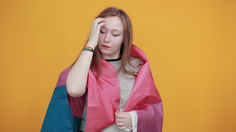 Mujer sosteniéndose en la cabeza, jugando con el pelo, cubierta bandera bisexual