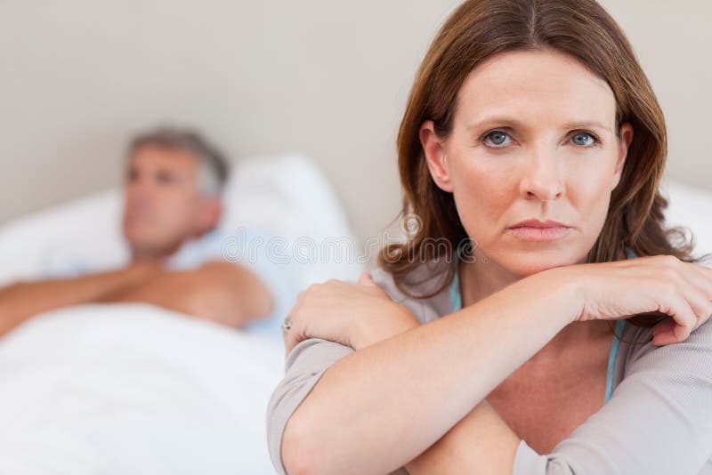 Mujer triste en la cama con el marido en fondo fotos de archivo libres de regalías Mujer triste en la cama con el marido en fondo fotos de archivo libres de regalías