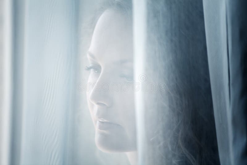 Mujer triste que mira hacia fuera la ventana