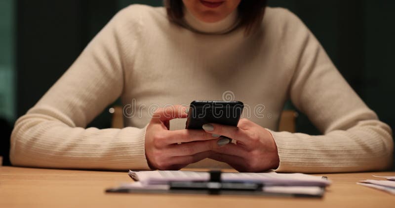 Mujer usa el teléfono en el escritorio por la noche en la oficina metrajes
