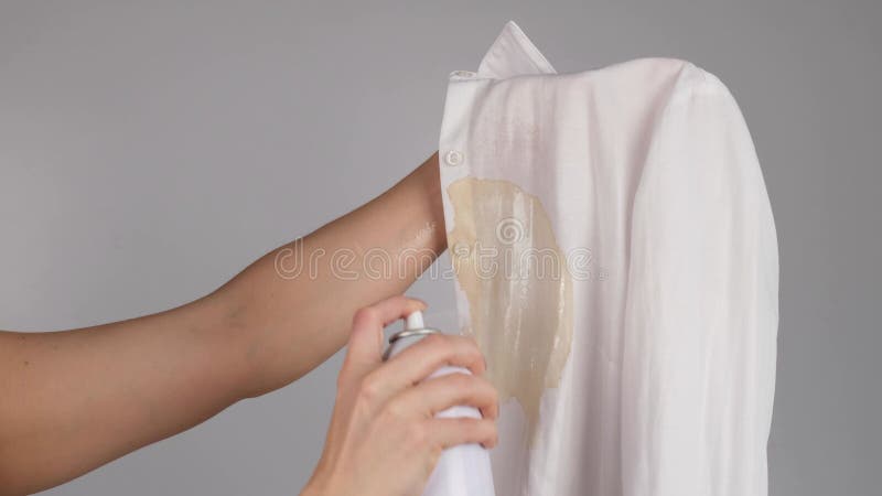 Mujer usa spray para remover manchas para camisa blanca de oficina con mancha de café. la chica usa lejía en su blusa almacen de video