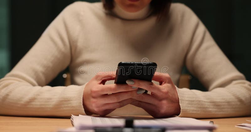 Mujer usa su teléfono en el escritorio por la noche en el lugar de trabajo almacen de metraje de vídeo