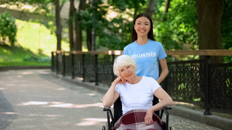 Mujer voluntaria sonriente y mujer discapacitada con aspecto de cÃ¡mara, caridad
