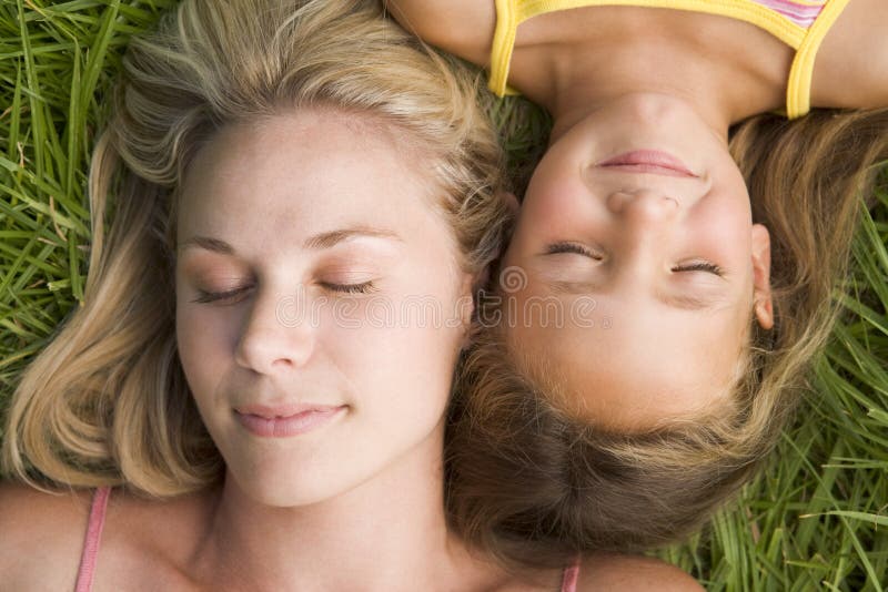 Mujer y chica joven que mienten en dormir de la hierba imagen de archivo libre de regalías Mujer y chica joven que mienten en dormir de la hierba imagen de archivo libre de regalías
