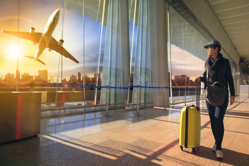 Mujer y equipaje que viajan que caminan en terminal y aire de aeropuerto foto de archivo Mujer y equipaje que viajan que caminan en terminal y aire de aeropuerto foto de archivo