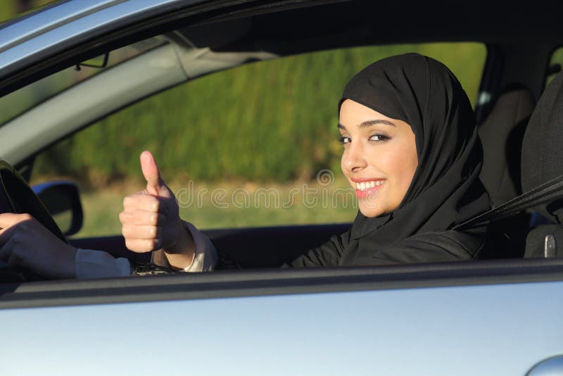 Mujer árabe feliz del saudí que conduce un coche con el pulgar para arriba imagen de archivo libre de regalías