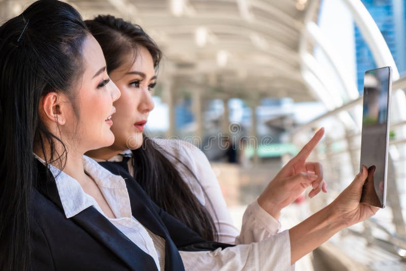 Mujeres de negocios que tienen charla del negocio y que usan la tableta del ordenador al aire libre fotografía de archivo libre de regalías Mujeres de negocios que tienen charla del negocio y que usan la tableta del ordenador al aire libre fotografía de archivo libre de regalías