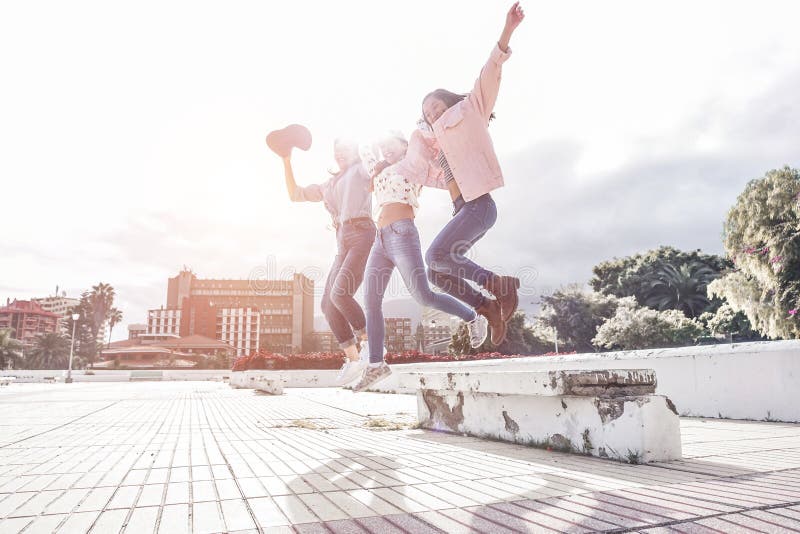 Mujeres del milenio asiáticas saltan al aire libre - Felices amigas divirtiéndose en el parque urbano - Generación z, jóvenes, jó foto de archivo