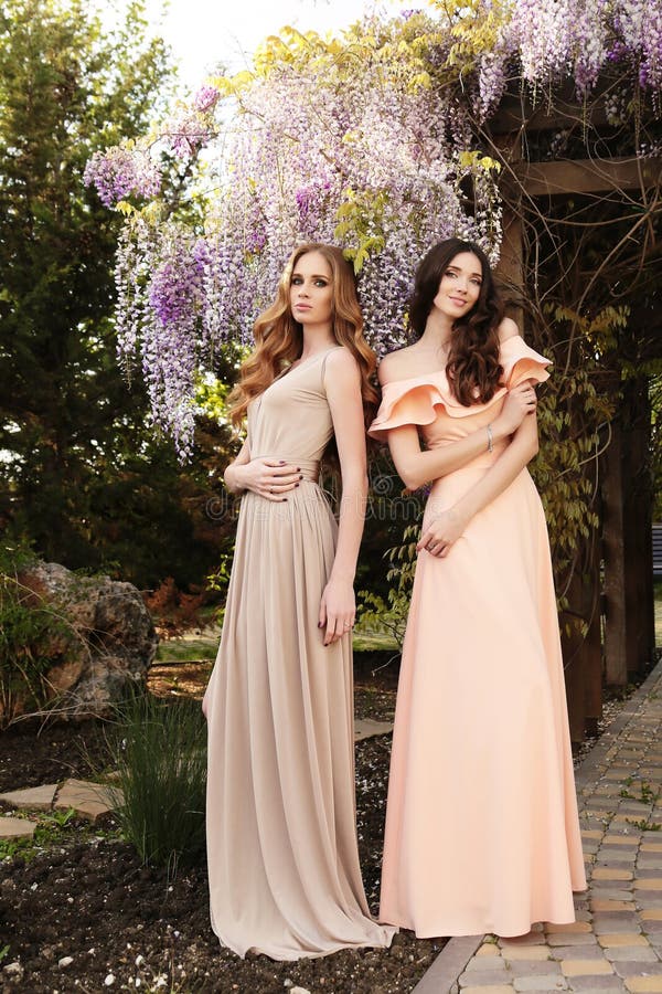 Mujeres En Los Vestidos Elegantes, Presentando En Jardín De La Primavera Del Flor Foto de archivo - Imagen de maquillaje, hembra: 71010032 Mujeres En Los Vestidos Elegantes, Presentando En Jardín De La Primavera Del Flor Foto de archivo - Imagen de maquillaje, hembra: 71010032