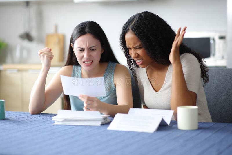 Mujeres furiosas revisando el estado de cuenta del banco en casa imágenes de archivo libres de regalías