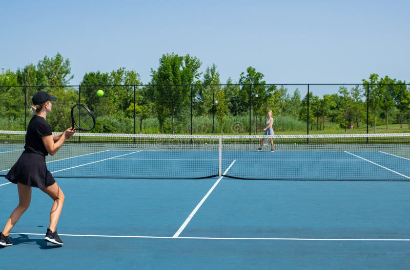 Mujeres jovenes de los deportes que juegan a tenis en la pista de tenis azul imágenes de archivo libres de regalías Mujeres jovenes de los deportes que juegan a tenis en la pista de tenis azul imágenes de archivo libres de regalías