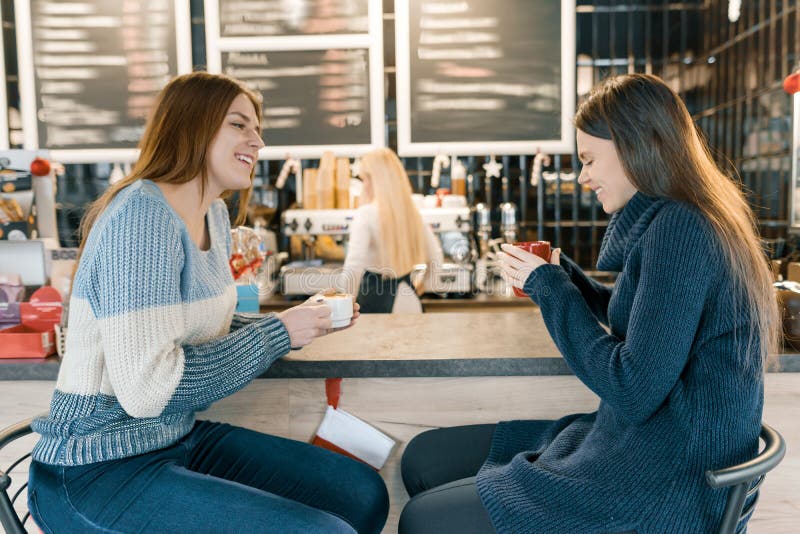 Mujeres jovenes que beben el café en el café, muchachas que se sientan cerca del contador de la barra imagenes de archivo Mujeres jovenes que beben el café en el café, muchachas que se sientan cerca del contador de la barra imagenes de archivo