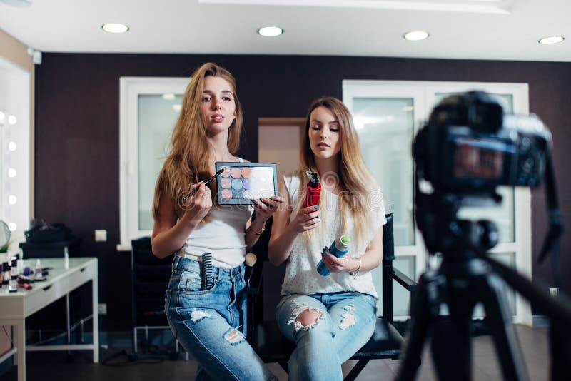 Mujeres jovenes que sostienen los productos de belleza que hacen un vídeo en los cosméticos para el videoblog fotos de archivo libres de regalías Mujeres jovenes que sostienen los productos de belleza que hacen un vídeo en los cosméticos para el videoblog fotos de archivo libres de regalías