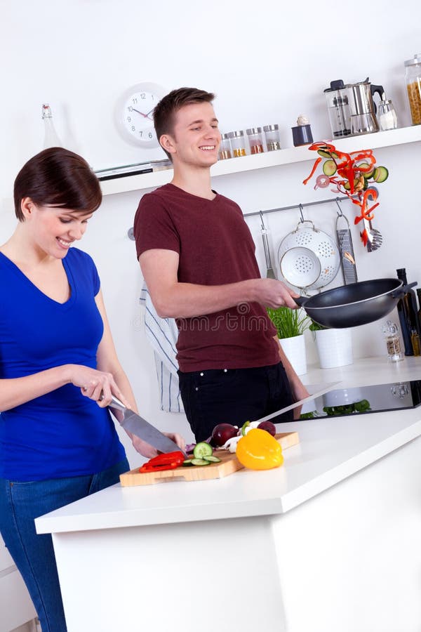 Mujer que taja las verduras y al hombre que mueven de un tirón la comida en la cacerola fotos de archivo libres de regalías Mujer que taja las verduras y al hombre que mueven de un tirón la comida en la cacerola fotos de archivo libres de regalías