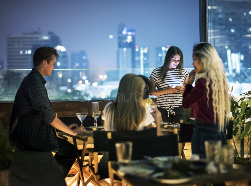 Mujeres jovenes que usan un smartphone en una noche de la cena que tiene no inter fotografía de archivo Mujeres jovenes que usan un smartphone en una noche de la cena que tiene no inter fotografía de archivo
