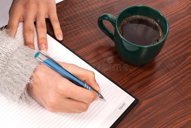 Mujeres que escriben en el cuaderno en el escritorio y el café de madera de la bebida imágenes de archivo libres de regalías Mujeres que escriben en el cuaderno en el escritorio y el café de madera de la bebida imágenes de archivo libres de regalías
