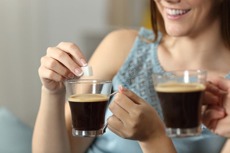 Mujeres que lanzan el azúcar en una taza de café fotos de archivo Mujeres que lanzan el azúcar en una taza de café fotos de archivo