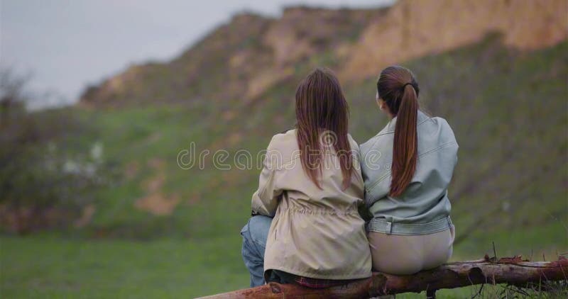 Mujeres turistas sentadas en un tronco y apuntando a la montaña de atrás almacen de video