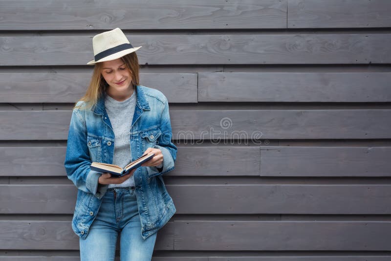 Jovem leu um livro junto à parede fotos de stock royalty free