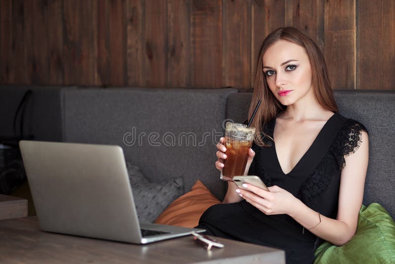 Mulher adorável nova com composição na moda dos olhos lindos e o equipamento à moda que bebe a xícara de café de vidro grande com fotografia de stock Mulher adorável nova com composição na moda dos olhos lindos e o equipamento à moda que bebe a xícara de café de vidro grande com fotografia de stock