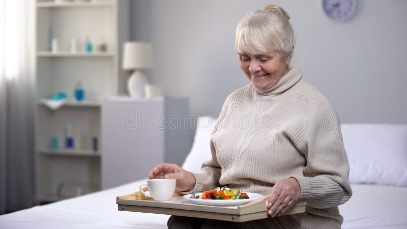 Mulher adulta de sorriso que come o jantar no lar de idosos, seguran?a social para povos envelhecidos fotografia de stock royalty free Mulher adulta de sorriso que come o jantar no lar de idosos, seguran?a social para povos envelhecidos fotografia de stock royalty free