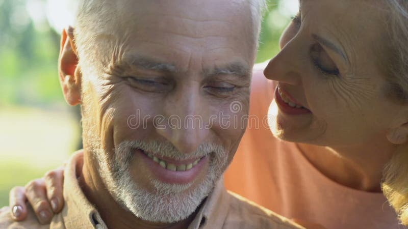 Mulher adulta que vêm equipar de atrás, pares que abraçam e que sorriem felizmente, amor