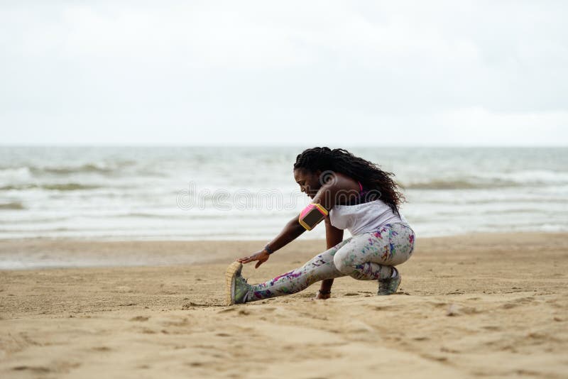 Mulher africana atrativa desportiva que faz exercícios na praia foto de stock Mulher africana atrativa desportiva que faz exercícios na praia foto de stock