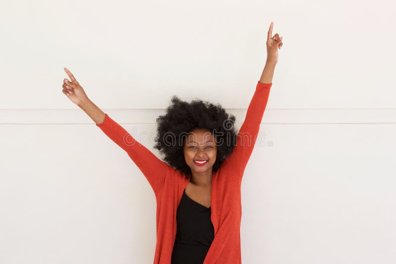 Portrait of happy young african woman with arms raised by white wall. Portrait of happy young african woman with arms raised by white wall