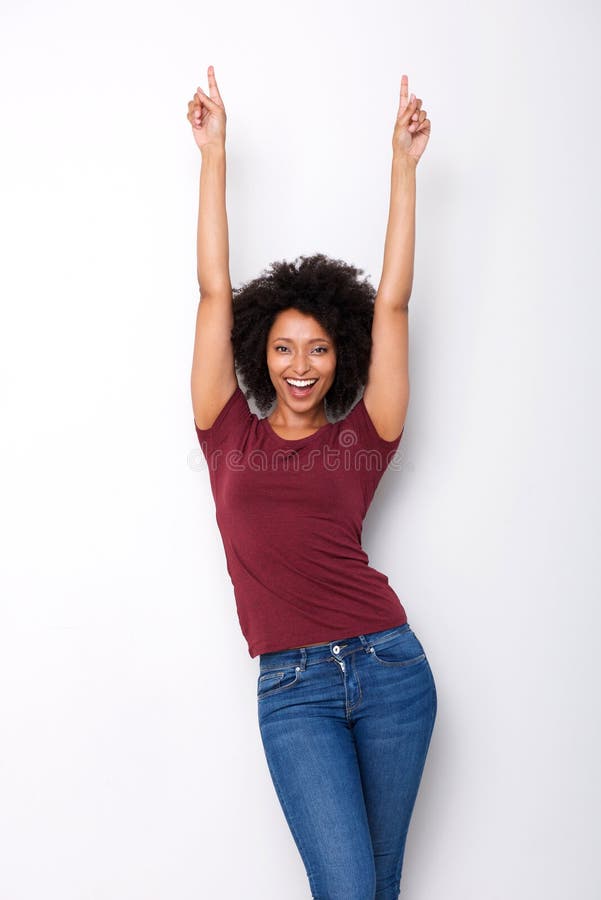 Mulher africana nova feliz que aponta os dedos acima no excitamento no fundo branco