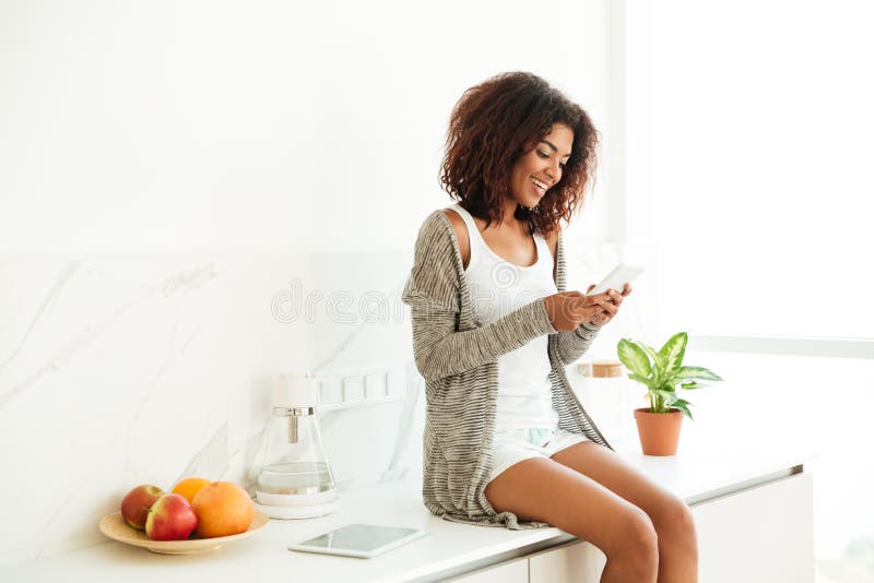 Mulher afro-americana nova bonita que texting no telefone celular foto de stock Mulher afro-americana nova bonita que texting no telefone celular foto de stock