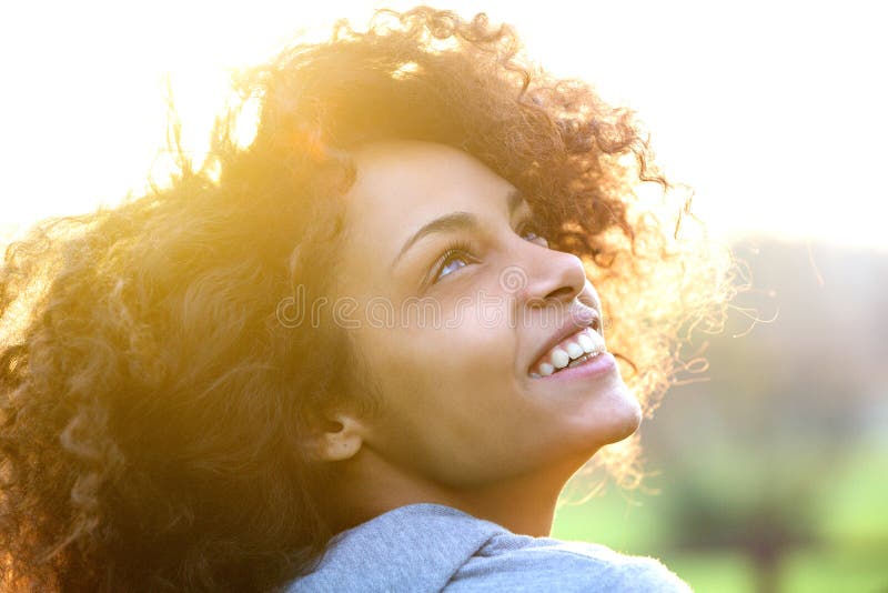 Jovem mulher afro-americana sorrindo e olhando para cima fotografia de stock